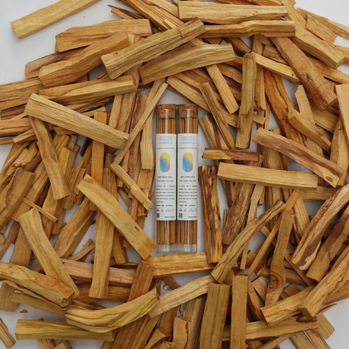 Palo Santo wooden sticks with two bottles of Palo Santo incense sticks on a white background